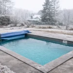 Piscina en invierno con agua limpia y parcialmente cubierta durante el mantenimiento invernal